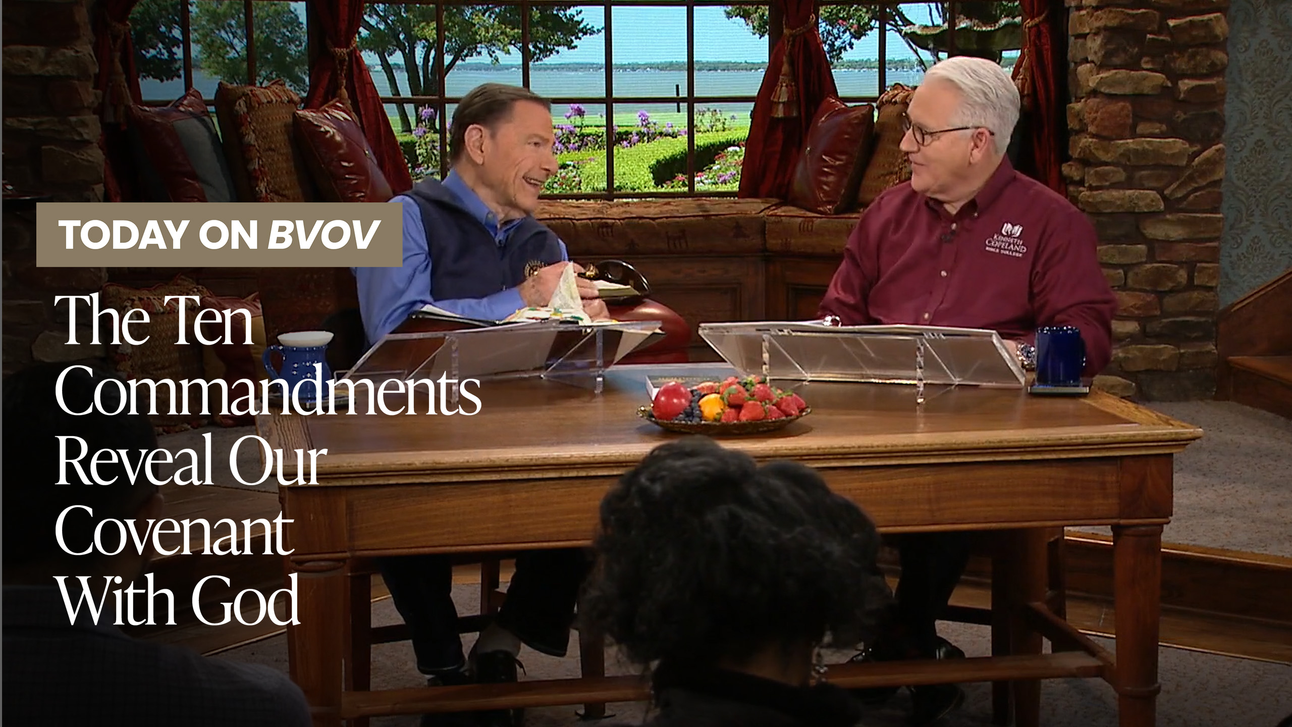 Kenneth Copeland and Greg Stephens in studio behind a beautiful wooden table. Both men have their Bibles on the table and are talking about God.